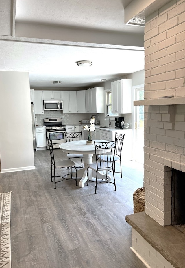 dining area with dark hardwood / wood-style floors, sink, and a brick fireplace