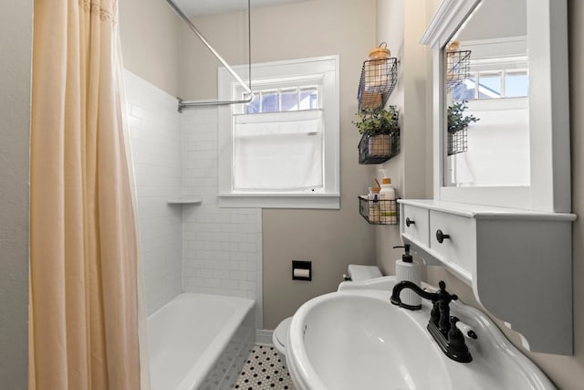 bathroom featuring a wealth of natural light, shower / tub combo with curtain, baseboards, and a sink