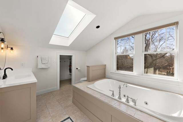 full bathroom with lofted ceiling with skylight, a sink, a whirlpool tub, double vanity, and a spacious closet