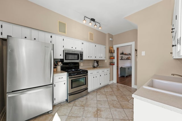 kitchen featuring light tile patterned floors, a sink, light countertops, white cabinets, and appliances with stainless steel finishes