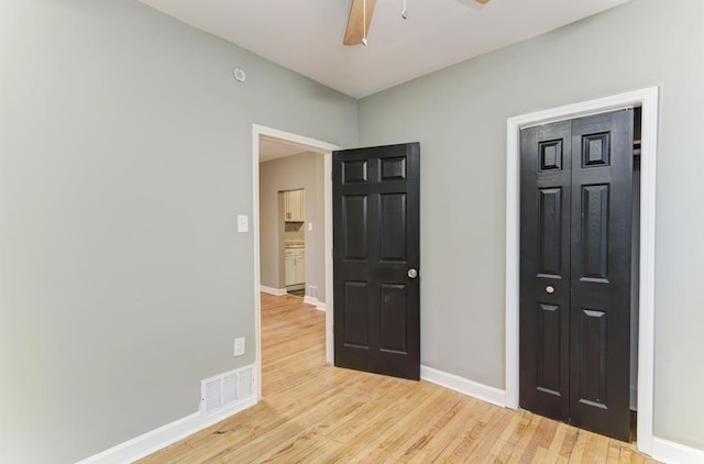 unfurnished bedroom featuring light wood-type flooring, a closet, and ceiling fan