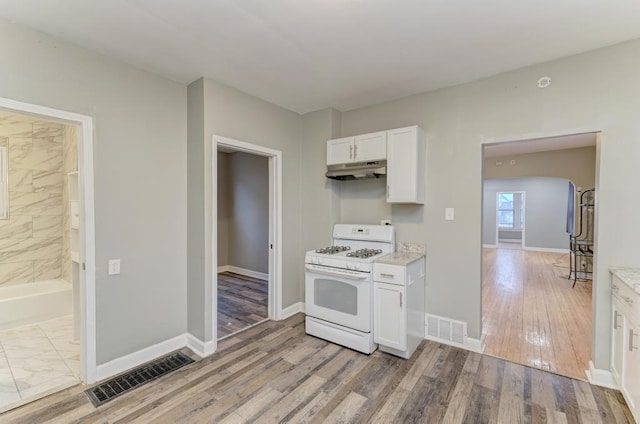 kitchen with white cabinets, light hardwood / wood-style flooring, and gas range gas stove