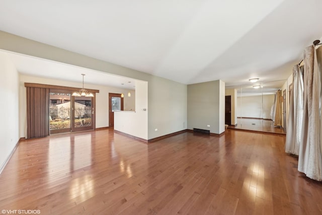 unfurnished living room with wood-type flooring and a notable chandelier