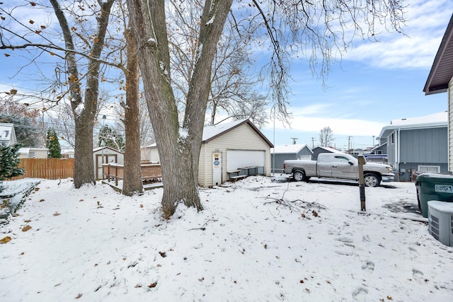 snowy yard with a garage and a storage shed