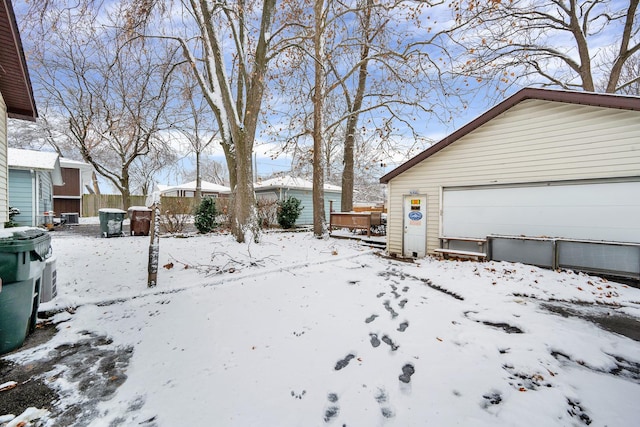 yard layered in snow featuring an outdoor structure and a garage