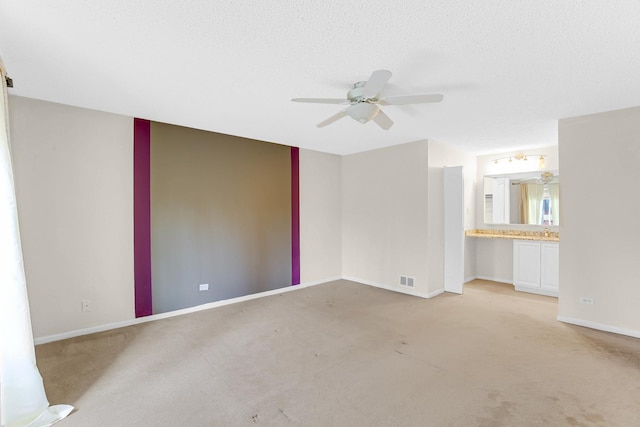 empty room featuring light carpet, ceiling fan, and a textured ceiling