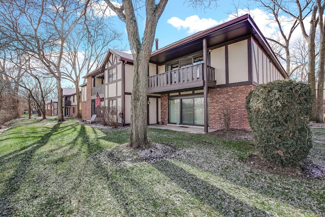 back of house featuring a lawn and a balcony