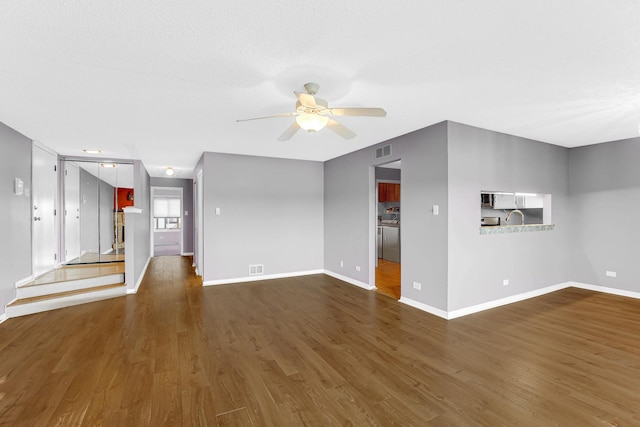 unfurnished living room with ceiling fan and dark wood-type flooring