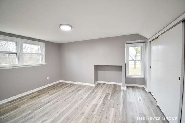 spare room featuring light wood-type flooring and vaulted ceiling