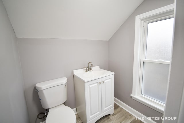 bathroom featuring hardwood / wood-style floors, vanity, vaulted ceiling, toilet, and plenty of natural light