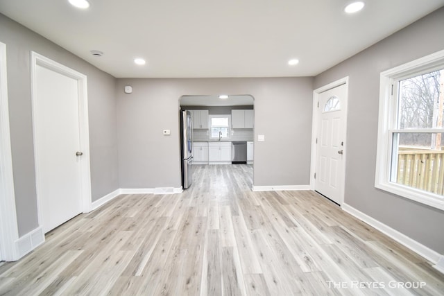 unfurnished living room featuring sink and light hardwood / wood-style flooring