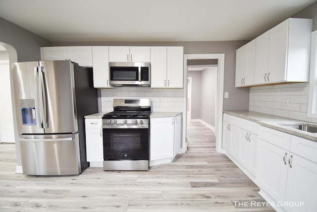 kitchen featuring white cabinets, light stone countertops, and stainless steel appliances