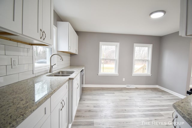 kitchen with white cabinetry, light stone counters, tasteful backsplash, and sink