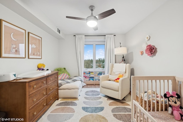 bedroom featuring ceiling fan and a nursery area