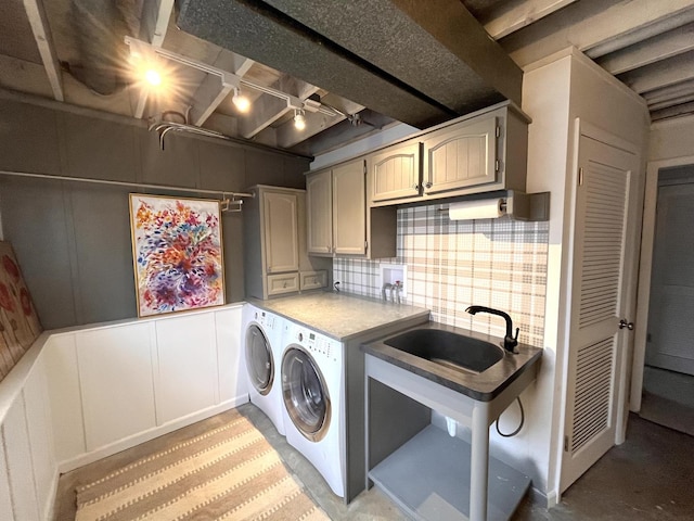 clothes washing area featuring sink, cabinets, and separate washer and dryer