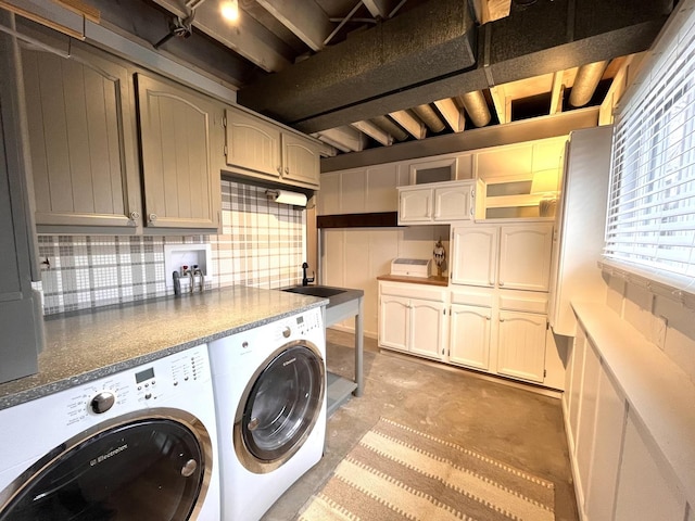 clothes washing area featuring cabinets, sink, and washer and clothes dryer