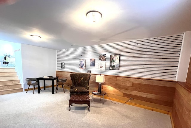 sitting room featuring wood walls and carpet floors