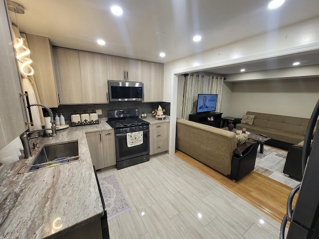 kitchen with light stone countertops, tasteful backsplash, sink, light brown cabinets, and black gas range