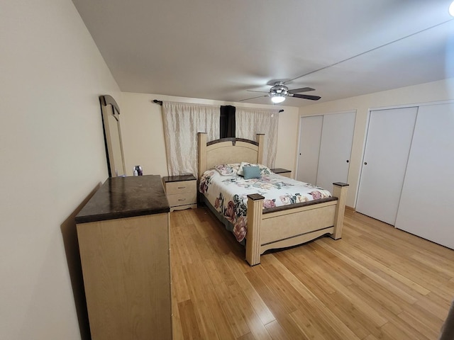 bedroom with hardwood / wood-style floors, ceiling fan, and two closets