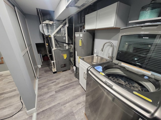 kitchen featuring heating unit, gas water heater, light hardwood / wood-style flooring, washer / clothes dryer, and white cabinetry