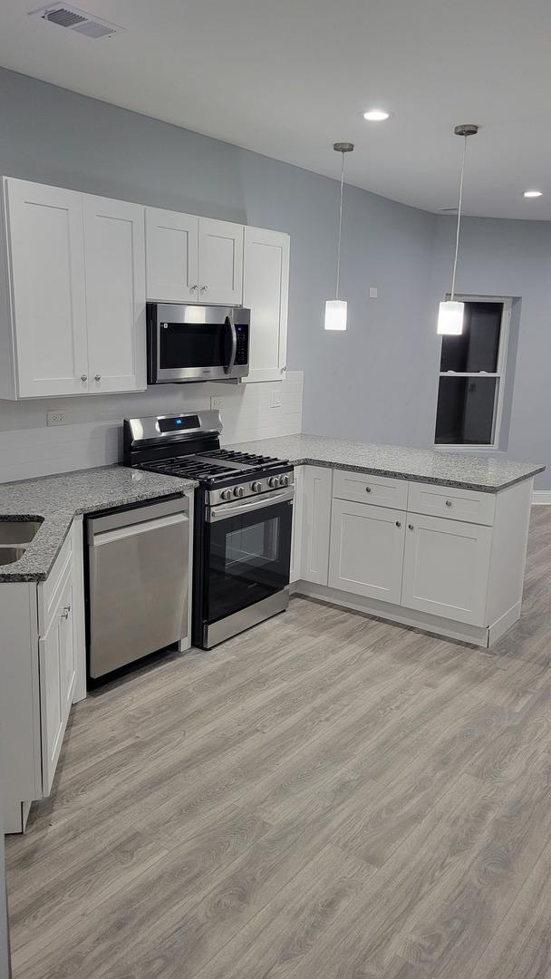 1918 S Kedzie Ave, Chicago, IL 60623 - kitchen with stainless steel appliances, a peninsula, white cabinetry, and recessed lighting