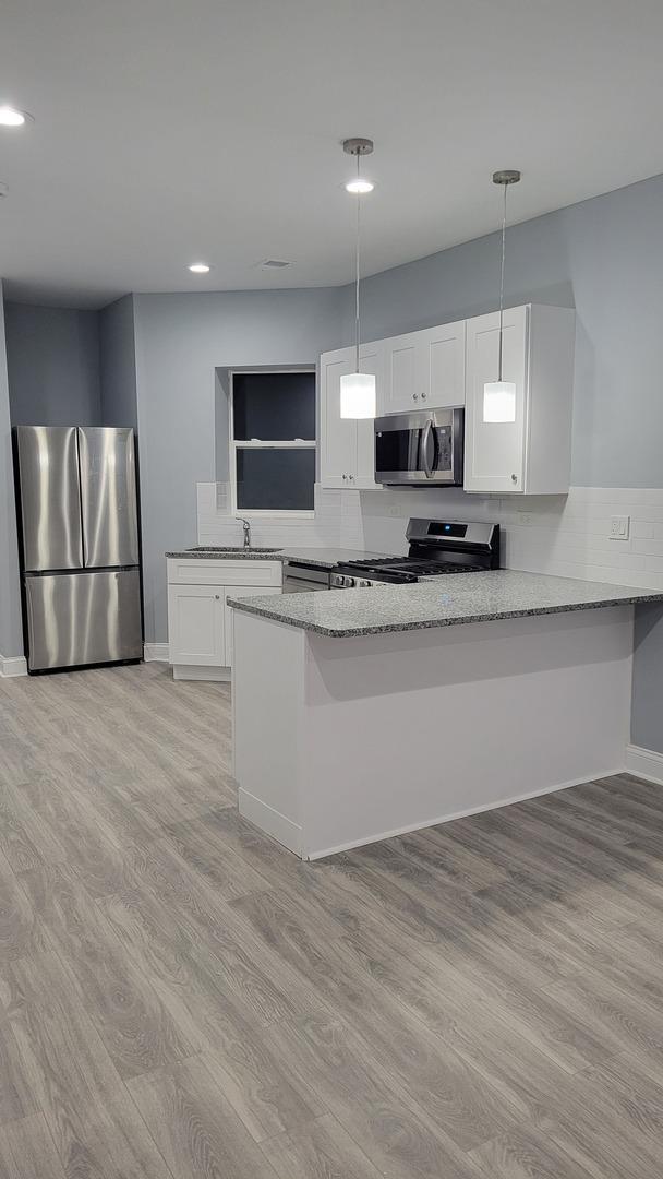 1918 S Kedzie Ave, Chicago, IL 60623 - kitchen with appliances with stainless steel finishes, light stone counters, white cabinets, light wood finished floors, and recessed lighting