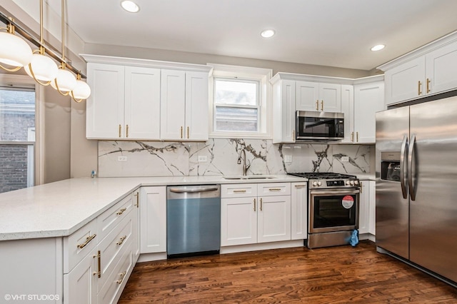 kitchen featuring sink, kitchen peninsula, decorative light fixtures, white cabinets, and appliances with stainless steel finishes