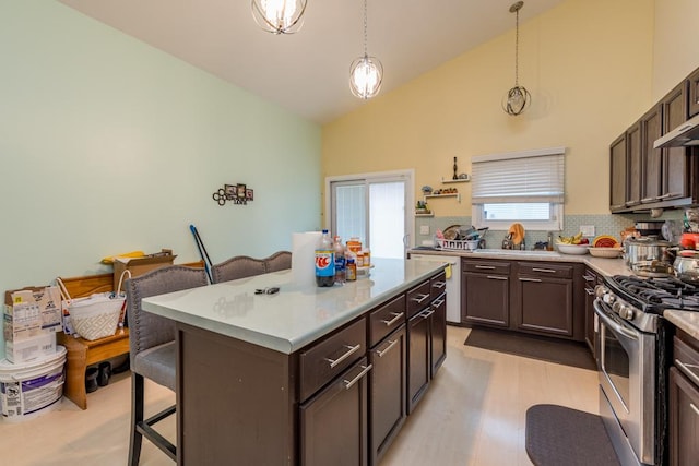 kitchen with tasteful backsplash, stainless steel range, a breakfast bar, pendant lighting, and a center island