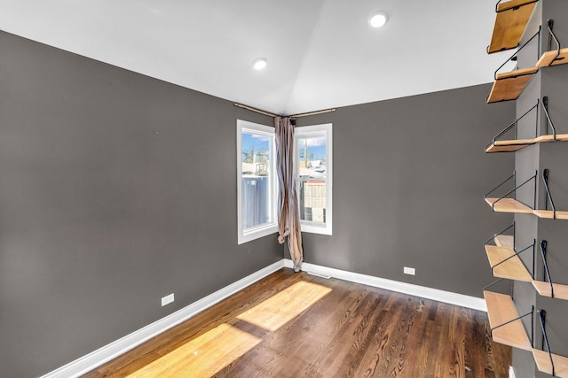 spare room featuring dark wood-type flooring and vaulted ceiling