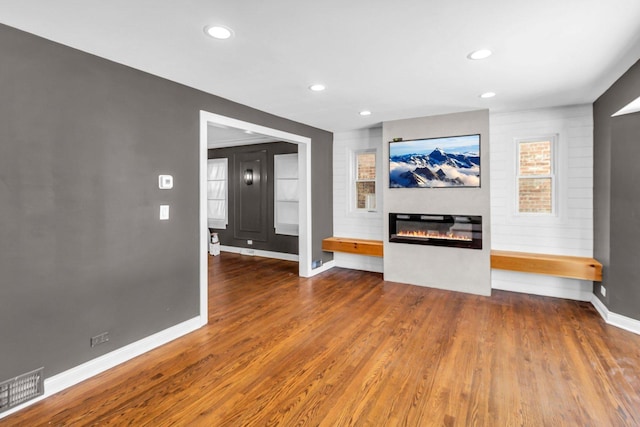 unfurnished living room featuring a large fireplace and wood-type flooring