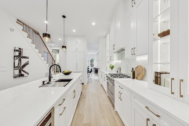 kitchen featuring hanging light fixtures, a sink, stainless steel stove, and white cabinetry