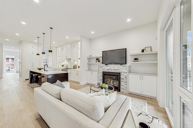 living area with recessed lighting, a glass covered fireplace, and light wood-style floors