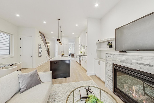 living area with baseboards, recessed lighting, a fireplace, and light wood-style floors