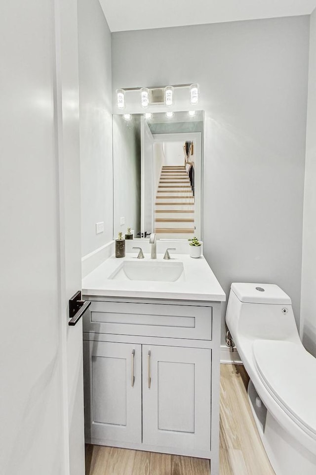 bathroom with toilet, wood finished floors, and vanity