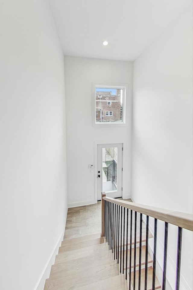 stairway featuring recessed lighting, wood finished floors, and baseboards