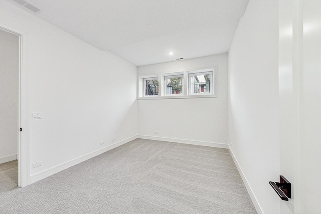 spare room with light colored carpet, visible vents, and baseboards