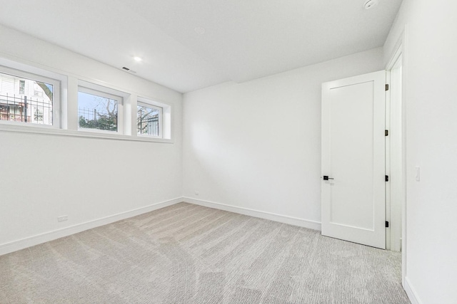 unfurnished room with baseboards, visible vents, and light colored carpet