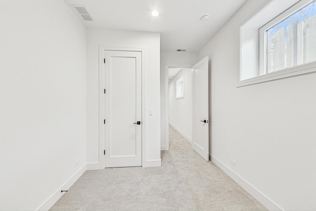 hallway with light carpet, baseboards, and visible vents