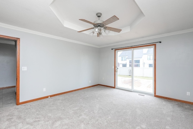 carpeted empty room with a tray ceiling, ceiling fan, and ornamental molding