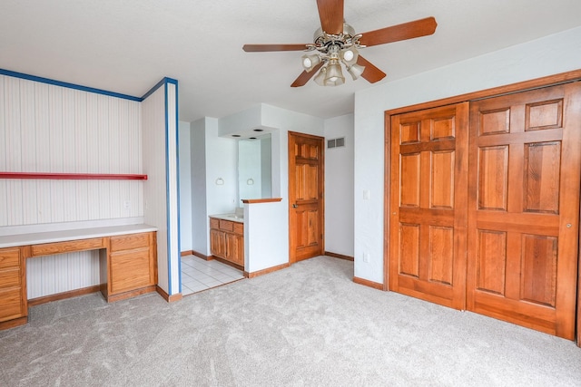 unfurnished bedroom with ensuite bathroom, ceiling fan, and light colored carpet