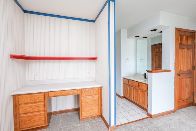 kitchen featuring built in desk, sink, and light carpet