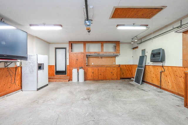 garage featuring white refrigerator with ice dispenser and wood walls