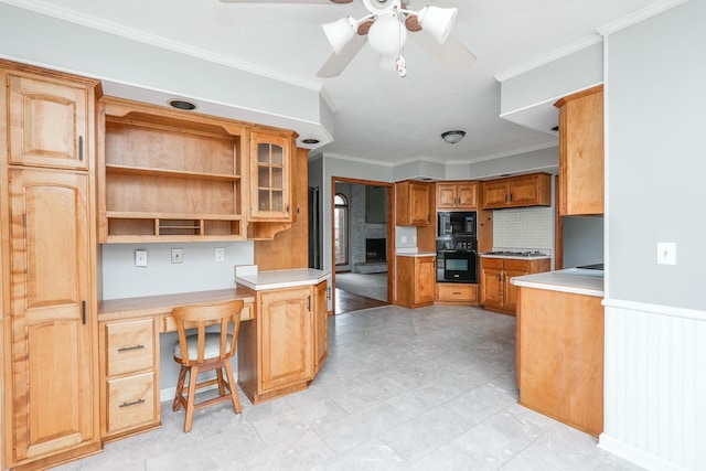 kitchen with ceiling fan, kitchen peninsula, black appliances, built in desk, and ornamental molding