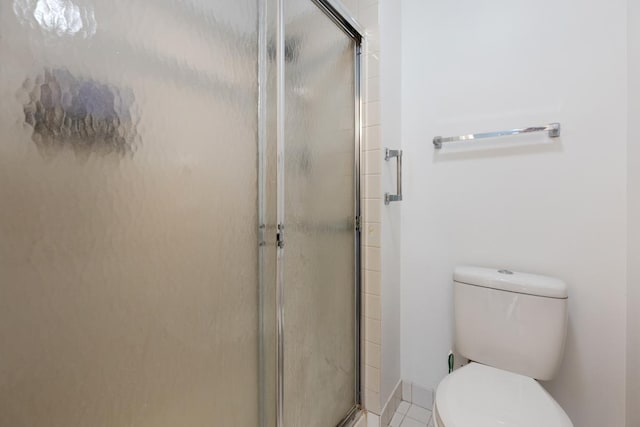 bathroom featuring tile patterned floors, toilet, and a shower with shower door