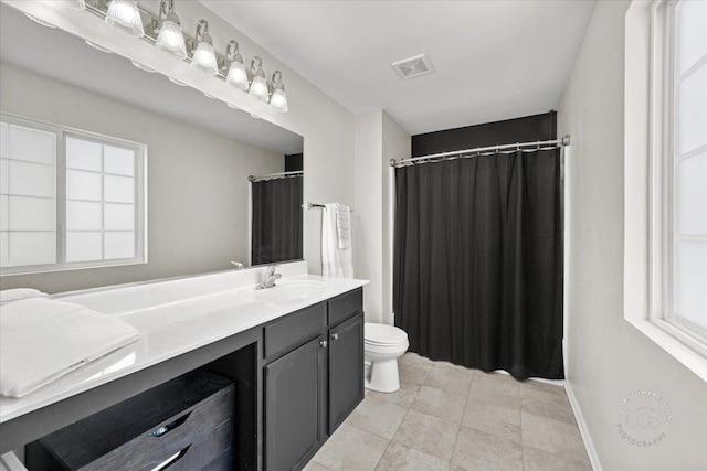 bathroom with toilet, a wealth of natural light, tile patterned floors, and vanity