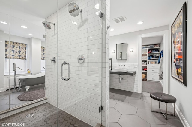 bathroom featuring tile patterned floors, sink, plus walk in shower, and tile walls