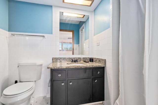 bathroom with tile patterned floors, vanity, tile walls, and toilet