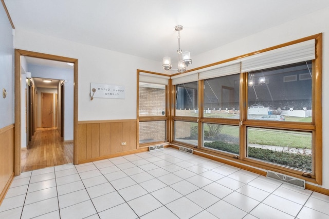 tiled empty room with wooden walls and a notable chandelier