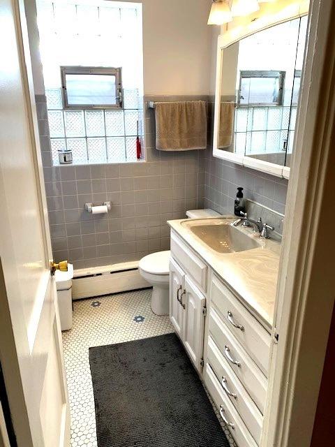 bathroom with vanity, tile patterned flooring, baseboard heating, tile walls, and plenty of natural light