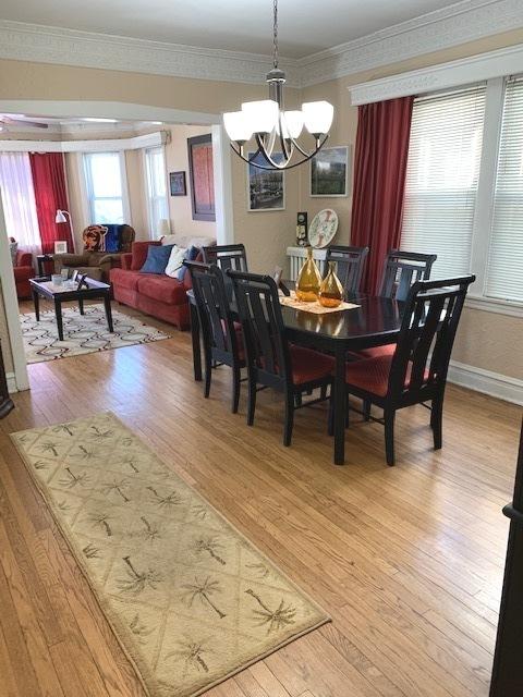 dining area featuring ornamental molding, hardwood / wood-style flooring, and a notable chandelier